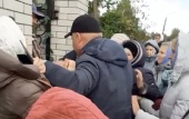 Schismatics beat Ukrainian Orthodox faithful who prayed near the fence of the seized church